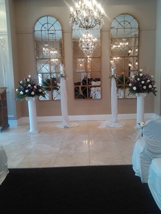 Ceremony: arched mirrors, pillars with florals