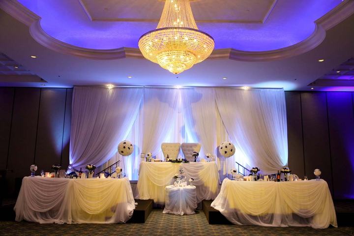 Head table white drapery, purple uplighting, crystal chandelier