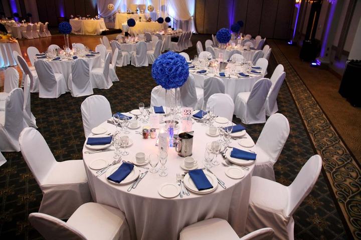 Round tables blue rose-ball centerpieces, white chair covers