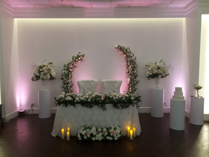 Sweetheart table, floral half-arches, pink uplighting