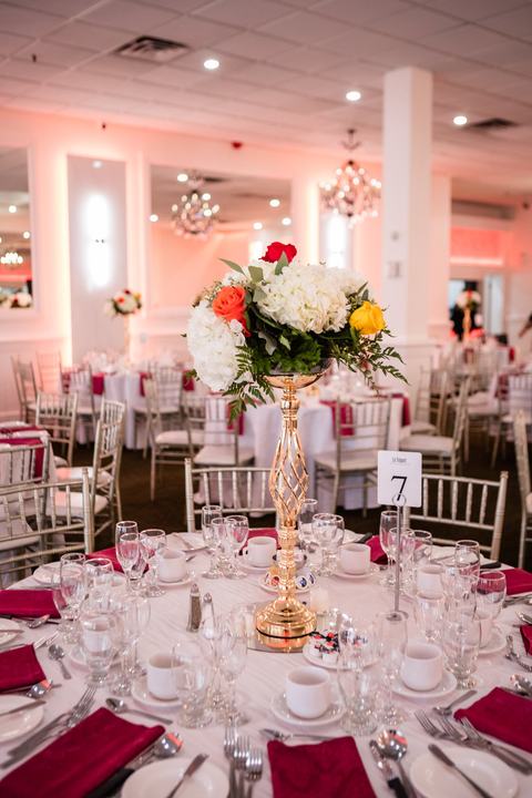Tall gold centerpiece red and white and orange roses, red napkins, table 7