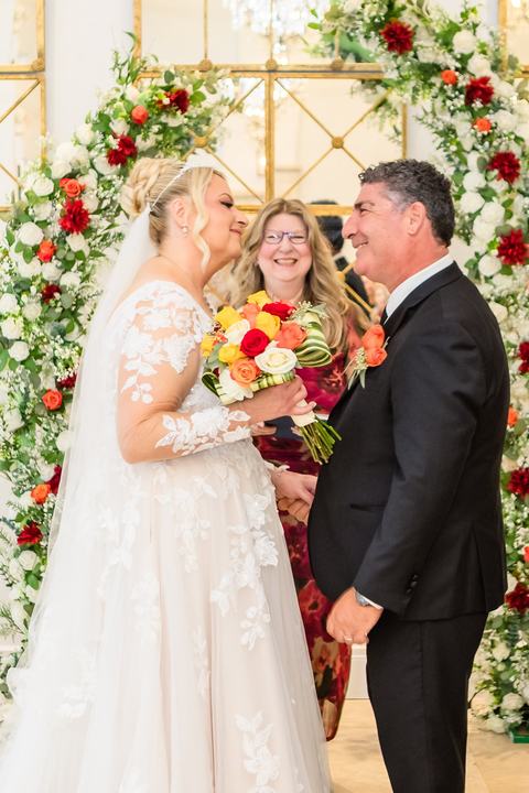 Couple at floral arch with guest