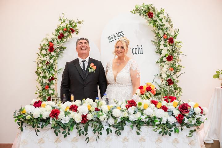 Couple at their head table under the floral arch