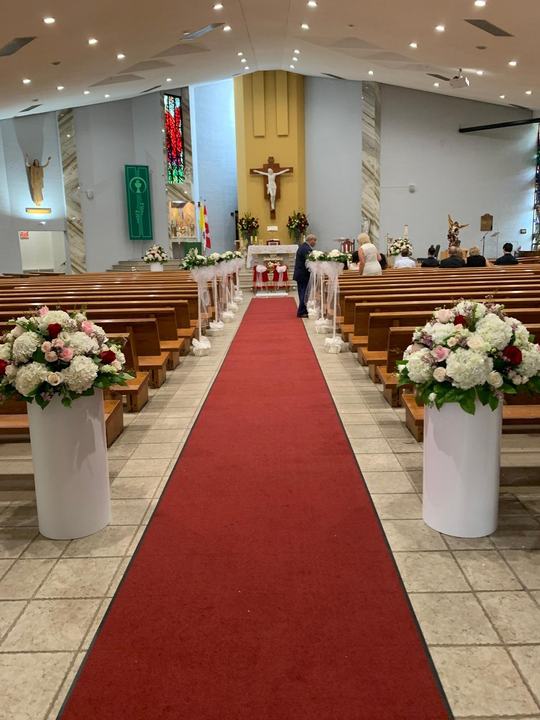 Church aisle red carpet pedestal florals