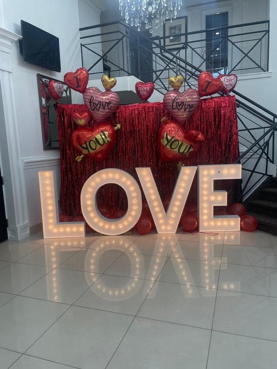 Marquee LOVE letters, red heart balloons, tinsel backdrop