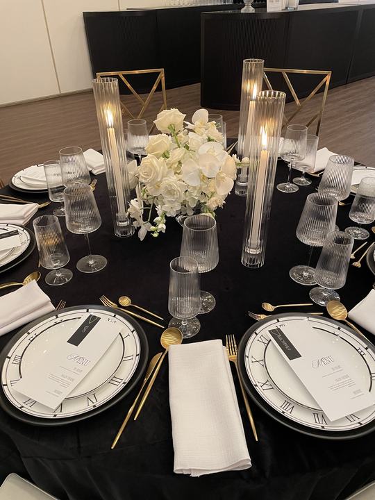 Black linen table, clock chargers, candles cylinders, white florals