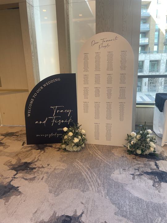 'Welcome to our wedding' arch sign and seating chart with florals